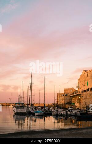 Hafen von Giovinazzo. Fischerboote vertäuten im kleinen Hafen im Sonnenuntergang. Italienische Stadt an der Adriaküste in der goldenen Stunde. Stockfoto