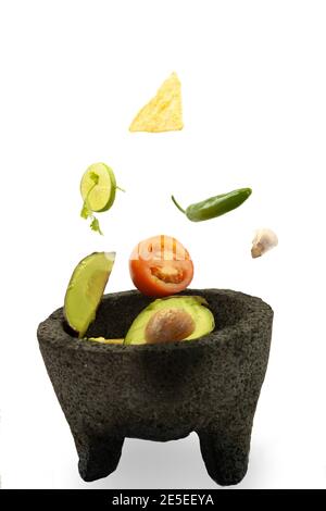 Fliegende Zutaten auf weißem Hintergrund Steineule, um Zitrone, Koriander, Chili, Knoblauch und Avocado zu zerkleinern Stockfoto