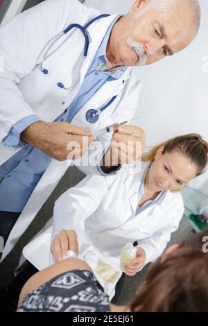 Leitender Arzt injiziert Patienten mit einer Spritze, um Blut zu sammeln Stockfoto