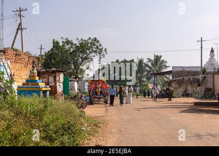 Siddanakolla, Karnataka, Indien - 7. November 2013: Hauptstraße durch Dorf mit Wanderern und Büffeln. Schrein und bescheidene Wohnungen auf Seite un Stockfoto