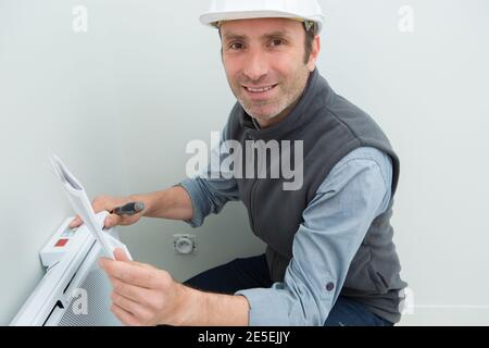 Mann, der eine Industrieheizung fixiert Stockfoto