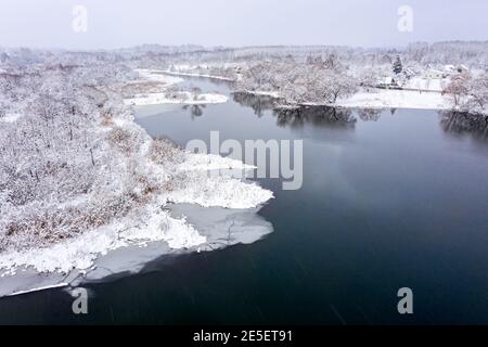 Panorama-Luftaufnahme des gefrorenen schneebedeckten Waldflusses. Winterlandschaft mit kleinem Dorf. Stockfoto