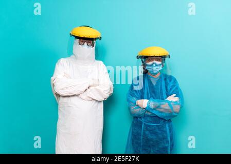 Stock Foto von medizinischen Mitarbeitern tragen Schutzanzug für covid19 Blick auf die Kamera vor blauem Hintergrund. Stockfoto
