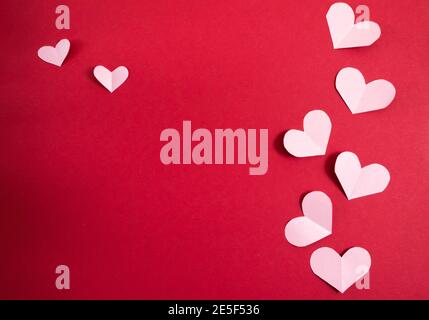 Papierherzen in verschiedenen Größen auf rotem Hintergrund. Abstrakter Hintergrund mit Papier geschnitten Formen. Sainte Valentine, Muttertag. Geburtstagskarte Stockfoto