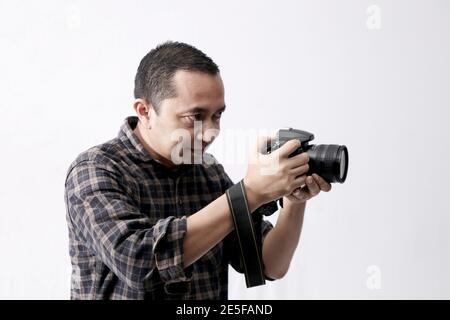 Ein Mann mit Kamera, ein Fotograf mit Kamera, der mit seiner digitalen Spiegelreflexkamera (Single Lens Reflex) Bilder macht. Stockfoto