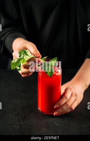 Frau macht blutigen mary Cocktail mit Sellerie Stockfoto