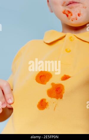 Schmutzige Ketchup Saucen Flecken auf einem gelben Kind T-Shirt. Kind ruiniert ihr T-Shirt mit Tomatensauce Essen Hot Dog. Stockfoto