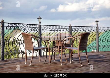 Terrasse mit Tisch und Stühlen. Interieur eines Sommercafés, Rattanmöbel im rustikalen Stil. Stockfoto