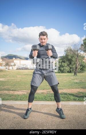 Athletic Mann tut Hocke und Rücken Übung und Cross-Training Mit Kurzhanteln Stockfoto