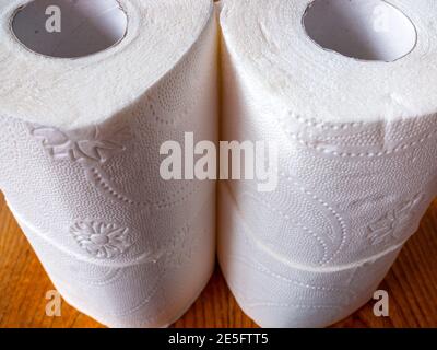 4 Rollen Toilettenpapier steht auf der Oberseite gestapelt Einander auf einem braunen Holztisch Stockfoto