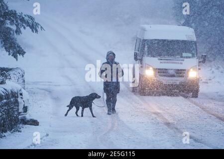 Ein Hundespaziergang und ein Lieferwagen machen sich auf einer schneebedeckten Straße in Slaley, Northumberland, auf den Weg, da Teile Großbritanniens in den nächsten Tagen mit bis zu 20 cm Schnee bedeckt werden könnten, während ein heftiger Regen auch Überschwemmungen auslösen könnte. Die Prognostiker sagten. Bilddatum: Donnerstag, 28. Januar 2021. Stockfoto