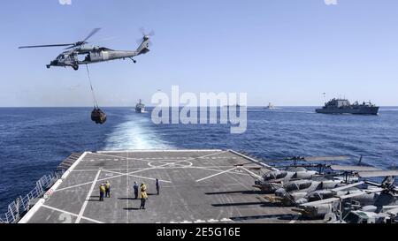 MH-60 Seahawk helihoisting Fracht von Flugdeck der USS Green Bay (LPD-20) mit USS Ashland (LSD-48), USS Bonhomme Richard (LHD-6), USS Preble (DDG-88) und USNS Amelia Earhart (T-AKE-6) im Hintergrund 150705 Stockfoto