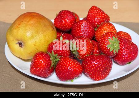 Teller mit Früchten als Erfrischung oder Dessert, Birne und süße rote Erdbeeren bereit zu essen Stockfoto