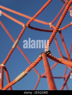 Kletterseilnetz mit blauem Himmel Hintergrund. Nahaufnahme eines Teils eines Sport- und Spielkomplexes. Stockfoto