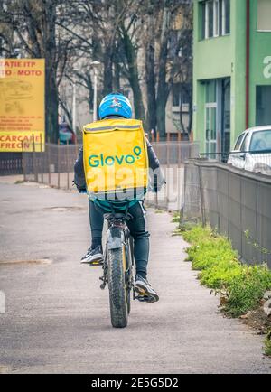 Bukarest/Rumänien - 12.25.2020: Glovo Kurier auf einem Fahrrad mit der gelben Liefertasche Stockfoto