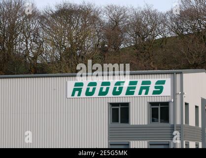 Rodgers Schild in grünen Buchstaben auf hellgrauem Metallgebäude Mit dunkelgrauer Zierleiste und Bäumen im Hintergrund Stockfoto