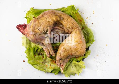 Rohes Kaninchenfleisch in Gewürzen auf Salatblättern. In Gewürzen, Zitronensaft, Pfeffer und Knoblauch marinieren. Draufsicht. Stockfoto