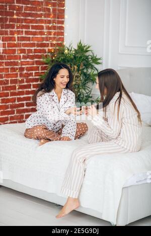 Zwei junge Mädchen im Schlafanzug sitzen auf einem Bett und Sprechen Stockfoto