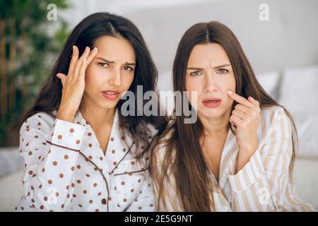 Zwei junge Mädchen im Schlafanzug berühren ihr Gesicht und suchen Besorgt Stockfoto