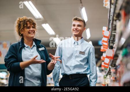 Lokaler Lebensmittelgeschäft Manager Ausbildung neuer männlicher Mitarbeiter. Frau erklärt Inventarsystem Supermarkt zu jungen Arbeiter. Stockfoto