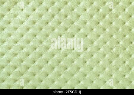Textur von hellgrünem Lederhintergrund mit Großbuchstaben-Muster, Makro. Olive Textil im Retro Chesterfield Stil. Vintage-Stoff im Hintergrund. Stockfoto