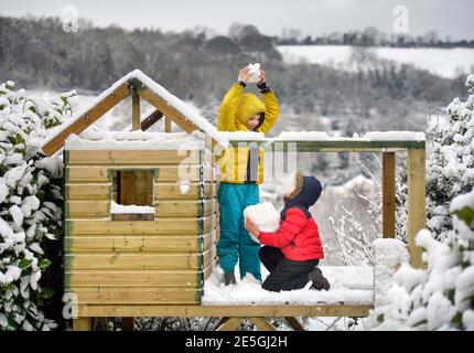 Zwei Jungen spielen mit Schneebällen in ihrem Baumhaus in Wotton-under-Edge, Gloucestershire UK Stockfoto