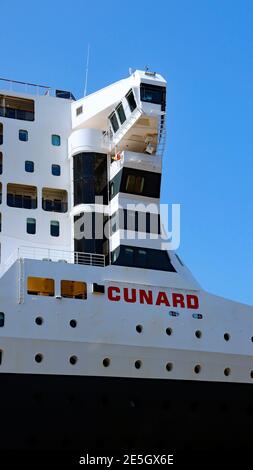 Schiffe überbrücken Cunards Queen Mary 2, während sie am Liverpools Cruise Terminal 2019 angedockt sind. Stockfoto