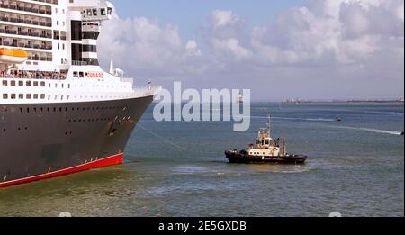 Cunards Queen Mary 2 bereitet sich darauf vor, den Hafen zu verlassen. Cunards Kreuzfahrtschiff Queen Victoria ist am Horizont zu sehen. Stockfoto