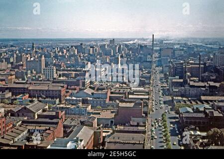 Ein Luftbild mit Blick nach Westen über Melbourne, Victoria, Australien im Jahr 1961, im zentralen Geschäftsviertel der Stadt. Die breite Straße ist Lonsdale Street. Die in den 1960er Jahren sichtbare Fertigungs- und Fabrikarbeit wurde fast vollständig durch weitaus höhere Gebäude mit einer Mischung aus Einzelhandel, Büro, Hotel und Wohnnutzung ersetzt. Im Hintergrund ist der Yarra River und das Hafenviertel der Stadt. Stockfoto