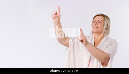 Banner, Langformat. Die ältere Frau zeigt ihre Zeigefinger nach oben. Weißer Hintergrund und leere Werbefläche. Stockfoto