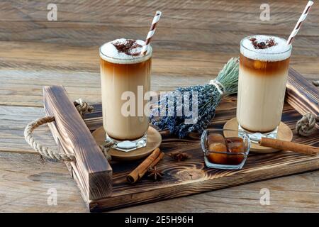Kaffee Tasse Latte mit hausgemachtem Lavendelsirup und Blumen auf einem Holztablett. Gemütliches Frühstück Stockfoto