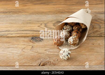 Energiebisse mit Nüssen, Samen, Trockenfrüchten und Honig - vegane oder vegetarische rohe Bio-Snack-Müslibisse auf Holzhintergrund. Stockfoto