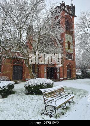 Eine schneebedeckte Bank vor einer Kirche. Stockfoto