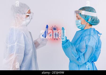 Zwei Ärzte in medizinischer Schutzkleidung mit Latexhandschuhen und einem vergrößerten Bild von Keimen dazwischen. Bekämpfung des Virus auf weißem Hintergrund. Stockfoto