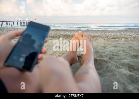 Die Beine des Mannes und er macht Fotos in der Nähe des Meeres Stockfoto