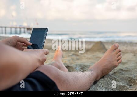 Die Beine des Mannes und er macht Fotos in der Nähe des Meeres Stockfoto