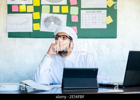 Der junge araber denkt in seiner Arbeit mit einem Ernst Blick auf sein Gesicht vor diesem Laptop Stockfoto
