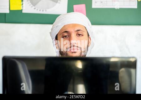 Der junge araber denkt in seiner Arbeit mit einem Ernst Blick auf sein Gesicht vor diesem Laptop Stockfoto
