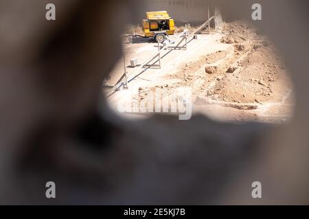 Ein Foto durch ein Loch für einen Arbeiter graben Nach oben die Grundlagen für ein neues Haus nach der Konstruktion in der Nachbarschaft mit Kompressor Stockfoto