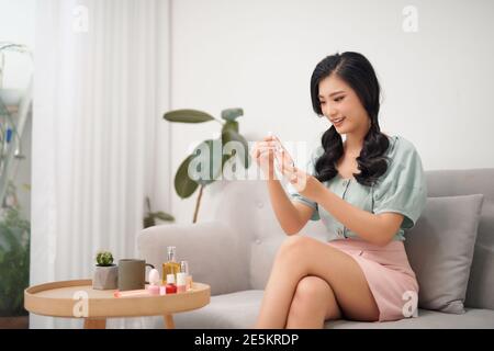 Make-up-Zeit. Junge asiatische Frau tun Make-up im Wohnzimmer Stockfoto