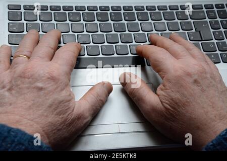 Hände eines älteren Mannes, der auf einem Laptop-Computer tippt Tastatur Stockfoto