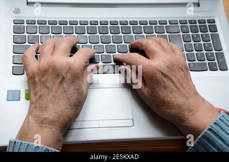 Hände einer älteren Frau, die auf einem Laptop-Computer tippt Tastatur Stockfoto