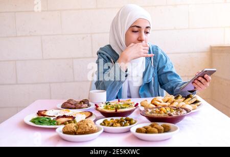 Muslimische Mädchen essen Frühstück und rufen ihre Freunde Stockfoto