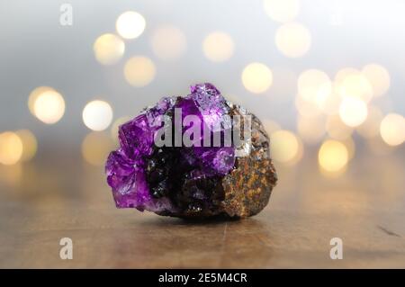 Fluorit (Fluorspat), violett-rosa auf altem Holztisch, Bokeh, Hygge-Ambiente Stockfoto