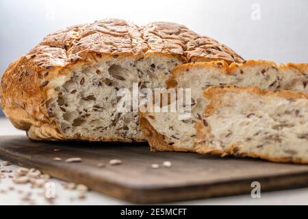 Close up Brotscheiben auf Servierbrett mit Flachs und Sonnenblumenkerne. Frisches, leckeres, rundes Weizenbrot mit Leinsamen. Stockfoto