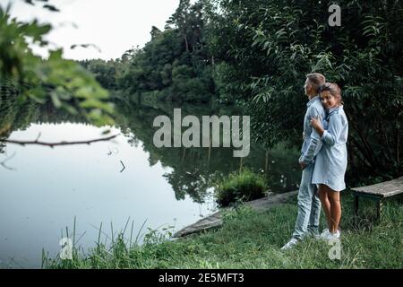 Das junge Paar umarmt und läuft am sonnigen Tag in der Nähe des Sees. Mann und Frau im Sommerurlaub. Konzept der schönen Familie. Selektiver Fokus. Stockfoto