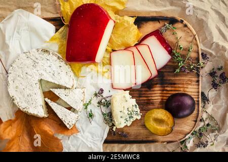 Set aus gereiftem Käse, Brie, Camembert mit Obst und Kräuter auf Holz und Bastelpapier Hintergrund Stockfoto
