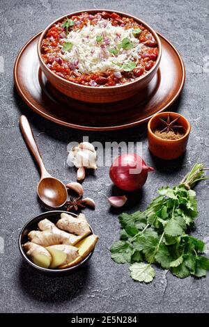 Rajma rote Bohne Masala, rote Bohne Nieren Curry, mit Reis in einer Tonschale auf einem Betontisch mit Zutaten, vertikale Ansicht von oben Stockfoto