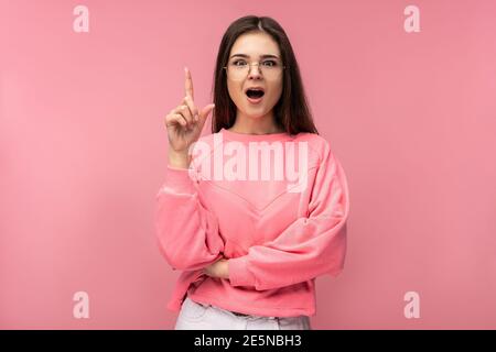 Foto von attraktiven jungen Frau in Brille bekam Idee, Wunder. Trägt lässige rosa T-Shirt weiße Hose isoliert rosa Farbe Hintergrund Stockfoto