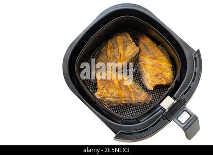 Frittierter Fisch in Schale mit Heißluft-Fritteuse oder ölfreier Fritteuse, Draufsicht, isoliert auf weißem Hintergrund. Das Konzept für modernes und gesundes Kochen. Stockfoto